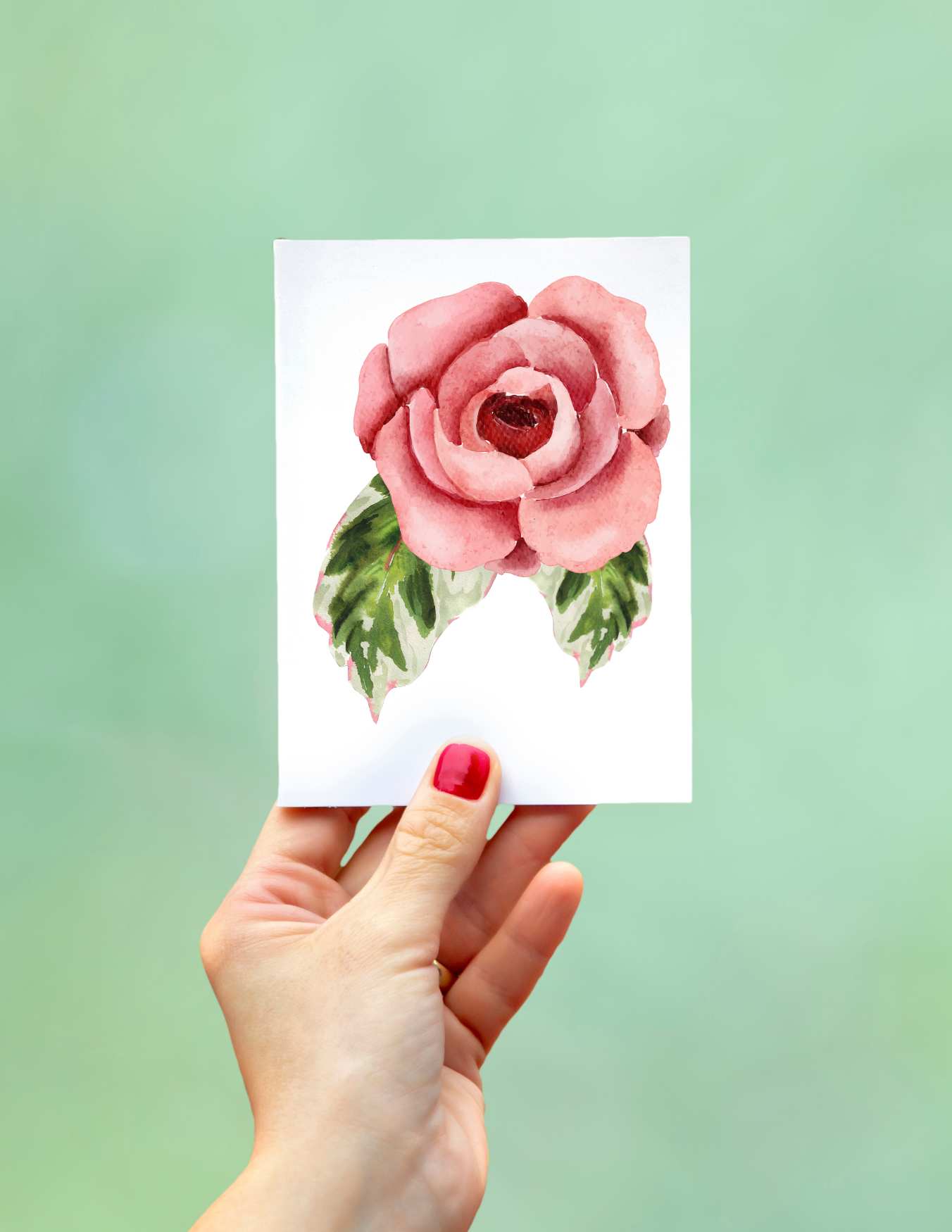 Woman's hand holding a tiny watercolor painting.