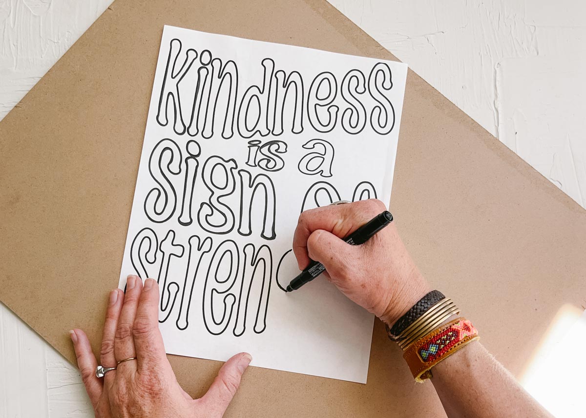 Jamie Shank's hands hand drawing a quote that says "kindness is a sign of strength."